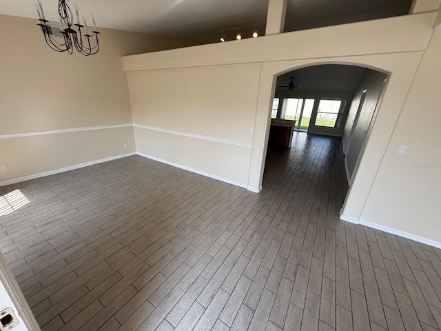 unfurnished room with baseboards, arched walkways, ceiling fan, and a chandelier