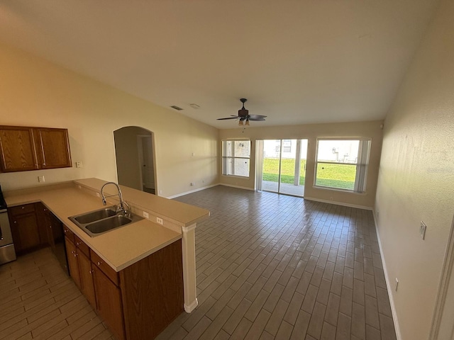 kitchen featuring a sink, baseboards, light countertops, ceiling fan, and a peninsula