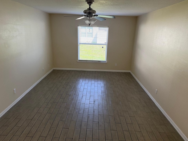 empty room with ceiling fan, baseboards, and dark wood-type flooring