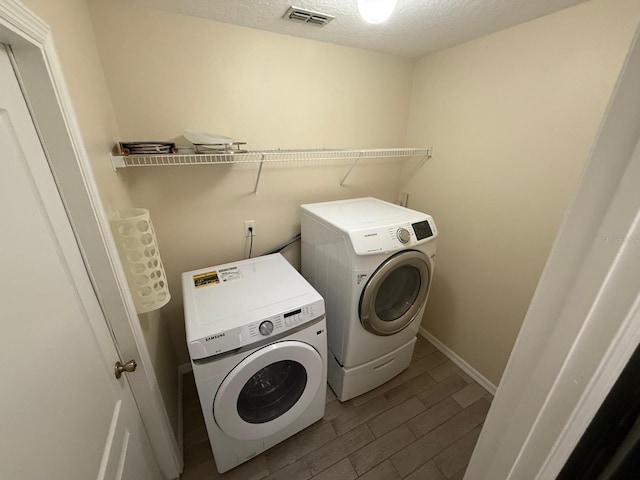 washroom with washer and dryer, wood tiled floors, a textured ceiling, and baseboards