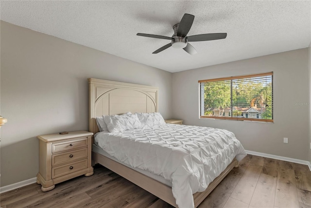 bedroom with wood finished floors, baseboards, a textured ceiling, and ceiling fan