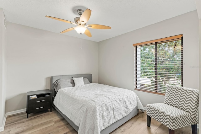 bedroom with light wood-style flooring, baseboards, and a ceiling fan