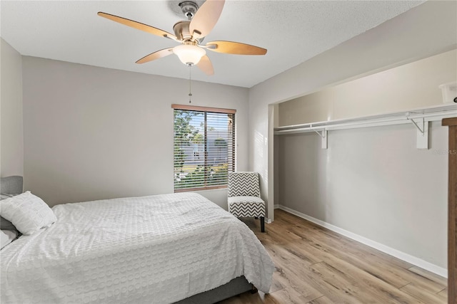 bedroom featuring light wood-style flooring, baseboards, a closet, and a ceiling fan