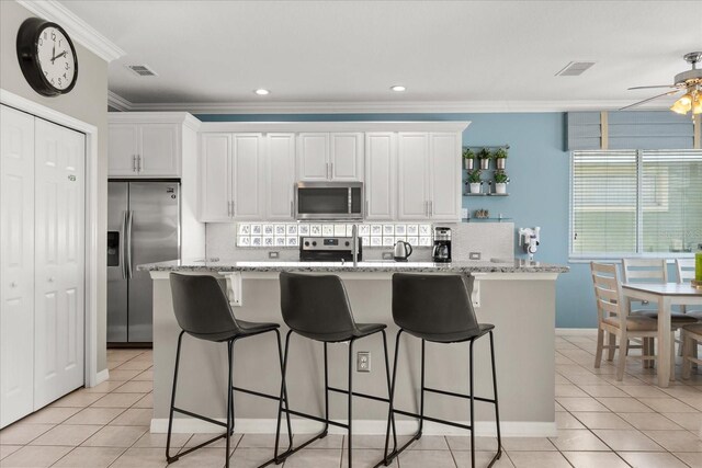 8522 Blue Horizon Ct, Kissimmee, FL 34747 - kitchen with appliances with stainless steel finishes, ornamental molding, white cabinetry, a ceiling fan, and light tile patterned floors