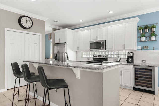 8522 Blue Horizon Ct, Kissimmee, FL 34747 - kitchen with wine cooler, appliances with stainless steel finishes, light tile patterned flooring, decorative backsplash, and white cabinets