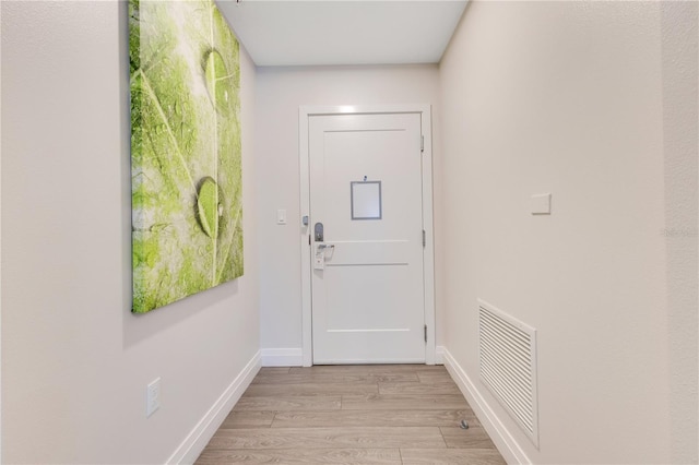 doorway with light wood-type flooring and baseboards