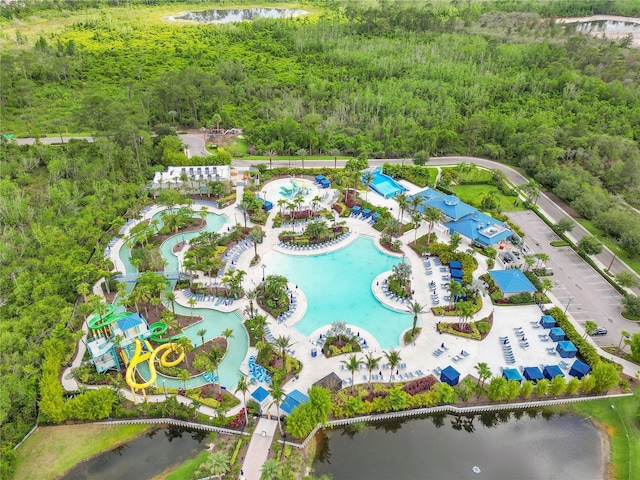 drone / aerial view of a pool area, a forest, and a nearby body of water