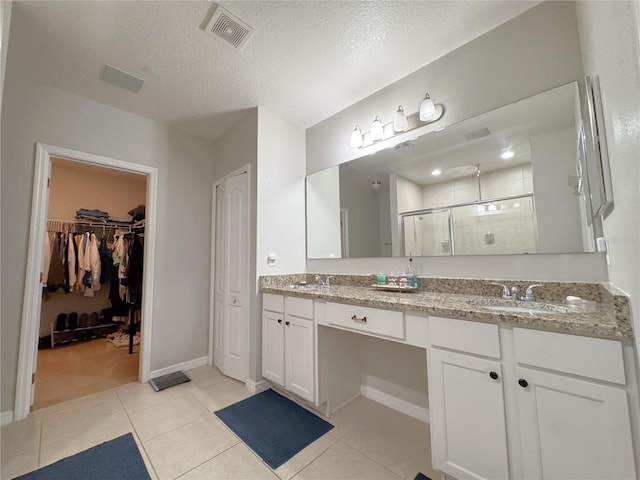 318 Briarbrook Ln, Haines City, FL 33844 - bathroom with a stall shower, tile patterned floors, double vanity, a walk in closet, and a textured ceiling
