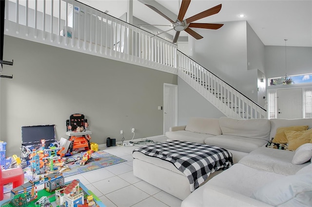 tiled living area featuring high vaulted ceiling, a ceiling fan, and stairs