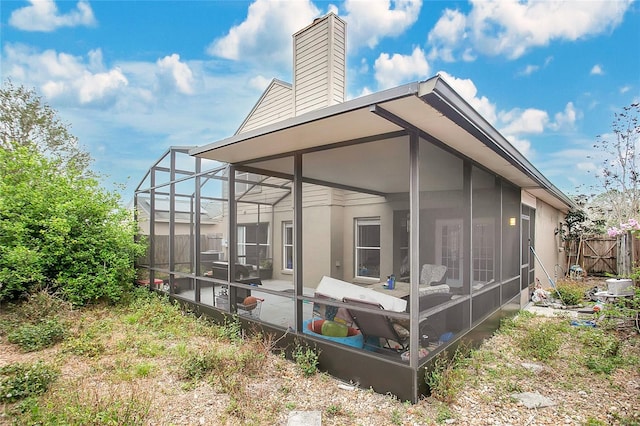 back of property with a chimney, a sunroom, fence, and a lanai