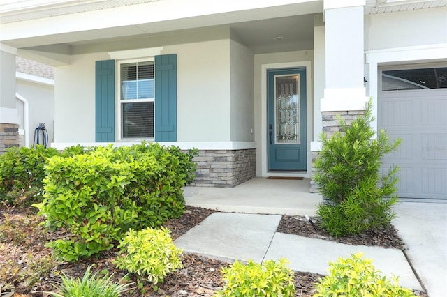 property entrance with covered porch, stucco siding, and a garage