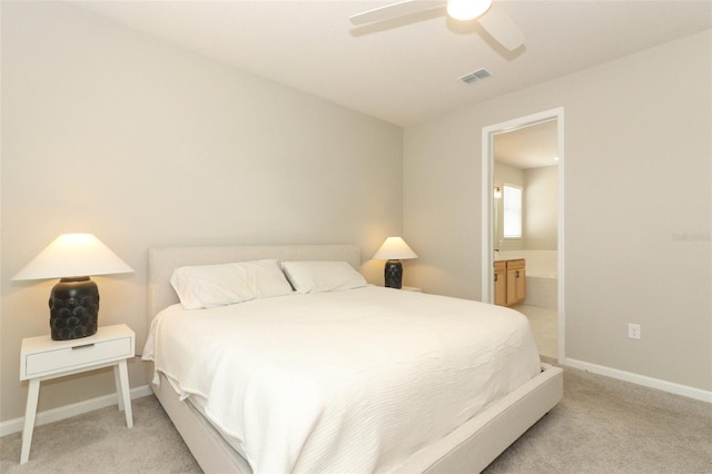 bedroom with light colored carpet, baseboards, ensuite bath, and a ceiling fan