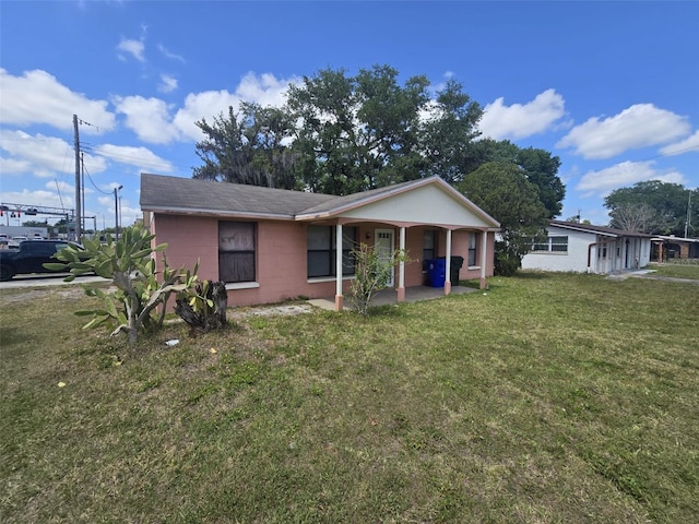 single story home featuring concrete block siding, a front lawn, and a porch