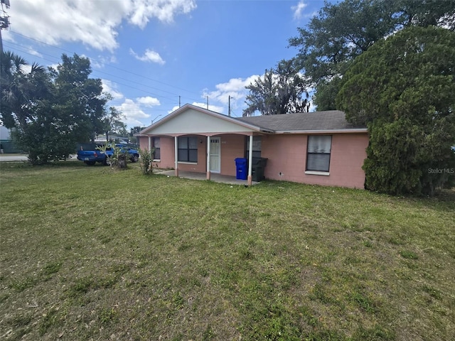 view of front of home with concrete block siding, a front yard, and a patio