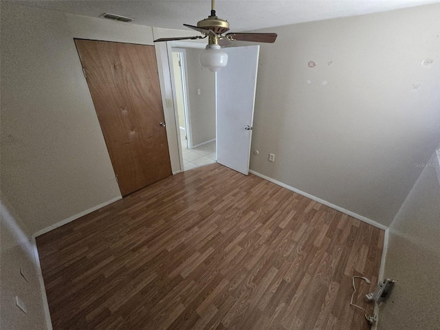spare room with wood finished floors, a ceiling fan, and baseboards