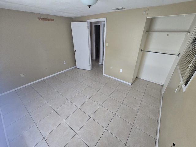 unfurnished bedroom featuring light tile patterned floors, baseboards, and a closet
