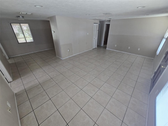 empty room with baseboards and light tile patterned floors