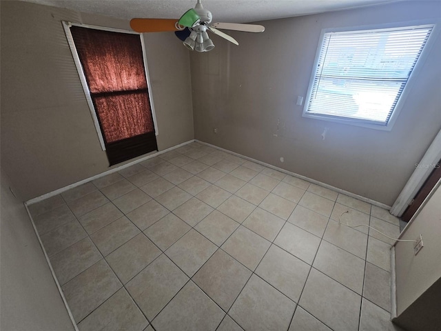 spare room with light tile patterned floors, ceiling fan, and baseboards