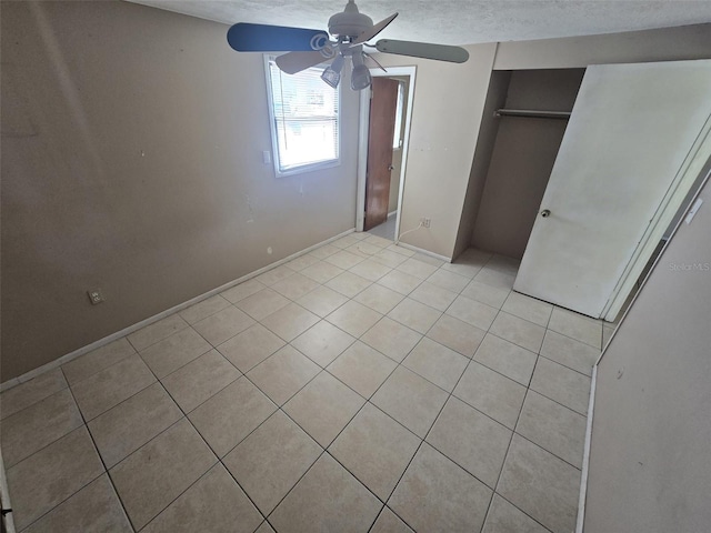 unfurnished bedroom featuring light tile patterned floors, a closet, a ceiling fan, and baseboards
