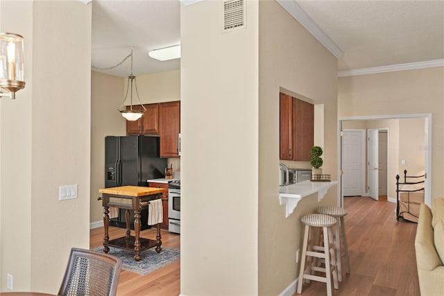 7628 Bay Port Rd Unit 43, Orlando, FL 32819 - kitchen with a breakfast bar area, brown cabinets, crown molding, light wood-type flooring, and light countertops