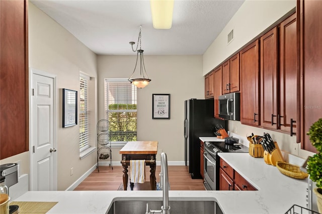 7628 Bay Port Rd Unit 43, Orlando, FL 32819 - kitchen with stainless steel appliances, light wood-style floors, a sink, and decorative light fixtures