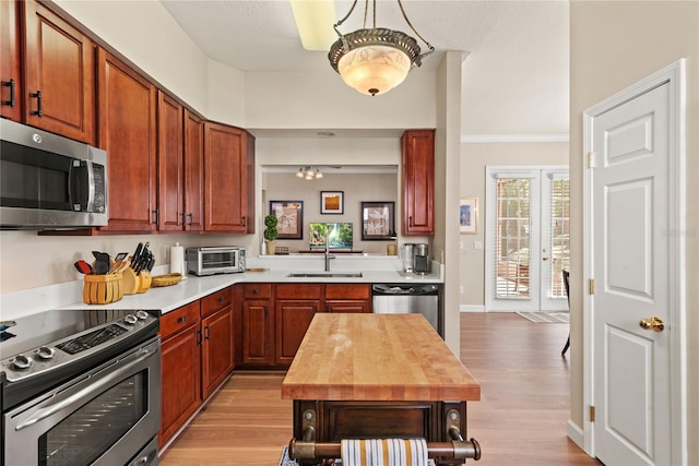 7628 Bay Port Rd Unit 43, Orlando, FL 32819 - kitchen with appliances with stainless steel finishes, a sink, light wood-style flooring, butcher block counters, and ornamental molding