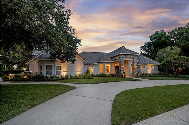 5025 Down Point Ln, Windermere, FL 34786 - french country home featuring stucco siding, a yard, stone siding, and curved driveway