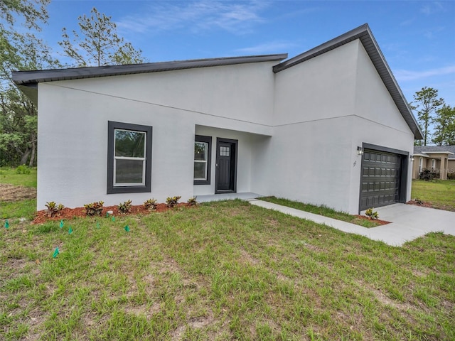 view of front of home featuring an attached garage, stucco siding, concrete driveway, and a front yard