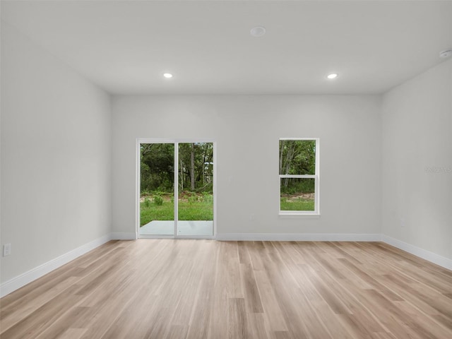 empty room featuring plenty of natural light, light wood-style flooring, recessed lighting, and baseboards