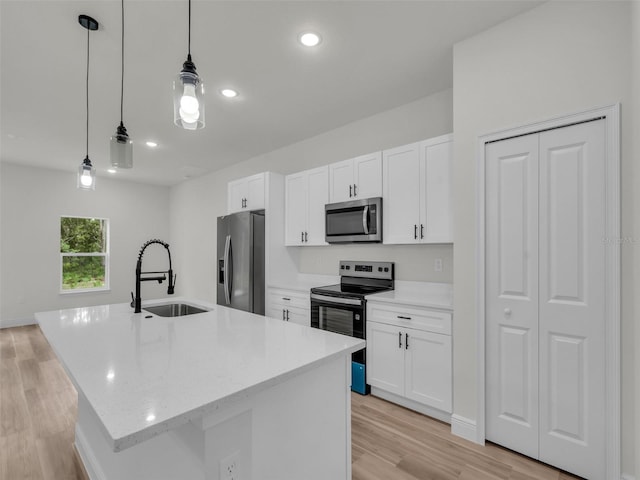 kitchen with appliances with stainless steel finishes, a kitchen island with sink, white cabinets, a sink, and recessed lighting