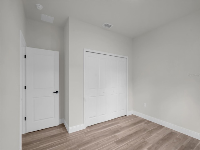 unfurnished bedroom featuring light wood-style flooring, a closet, and baseboards