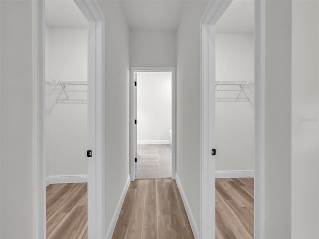 hall with light wood-type flooring and baseboards