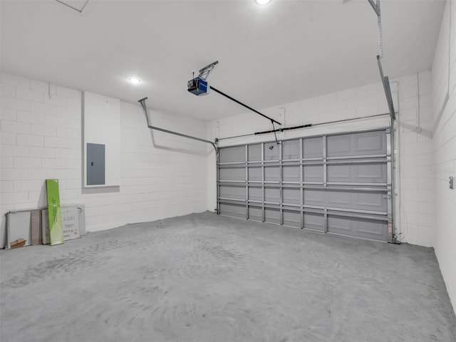 garage with a garage door opener, electric panel, and concrete block wall
