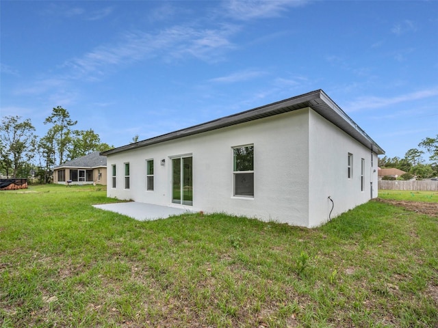 back of property featuring stucco siding, a lawn, and a patio