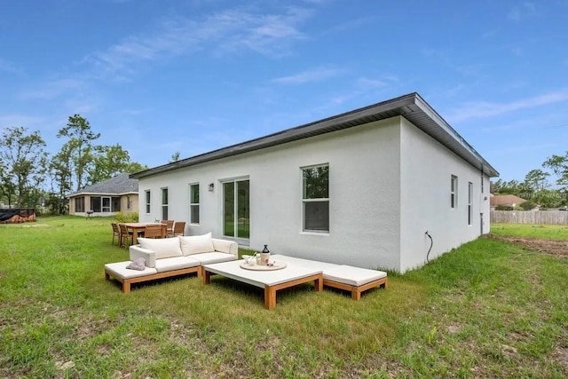 rear view of house with outdoor lounge area, a wooden deck, stucco siding, and a lawn