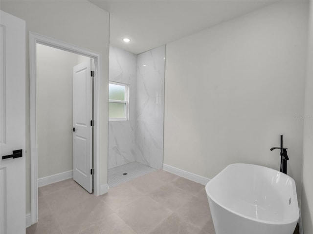 bathroom with baseboards, a freestanding tub, a marble finish shower, and recessed lighting