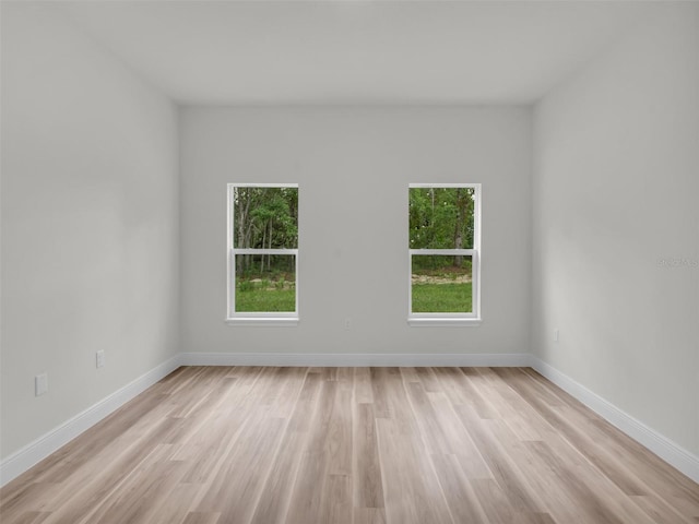 unfurnished room with healthy amount of natural light, light wood-style flooring, and baseboards