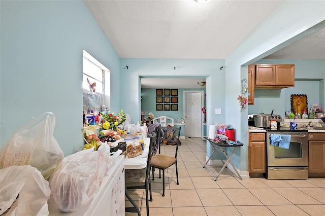 1508 Roger Babson Rd, Orlando, FL 32808 - kitchen featuring electric range, light tile patterned flooring, light countertops, a textured ceiling, and brown cabinetry