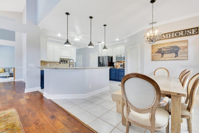 1837 Sweetwater W Cir, Apopka, FL 32712 - kitchen featuring stainless steel appliances, blue cabinetry, white cabinetry, ornamental molding, and pendant lighting