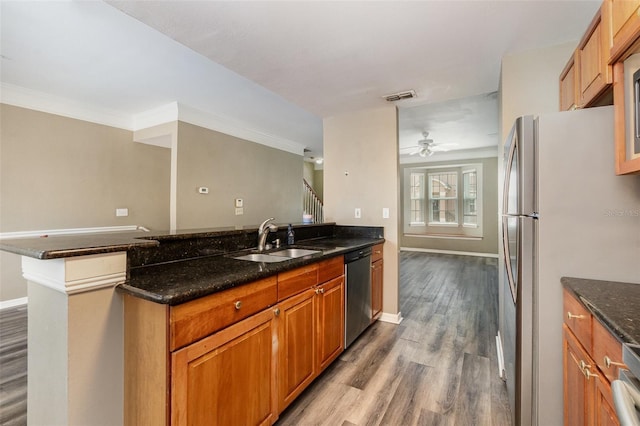 6611 Time Square Ave Unit 103, Orlando, FL 32835 - kitchen featuring appliances with stainless steel finishes, a sink, wood finished floors, dark stone countertops, and crown molding