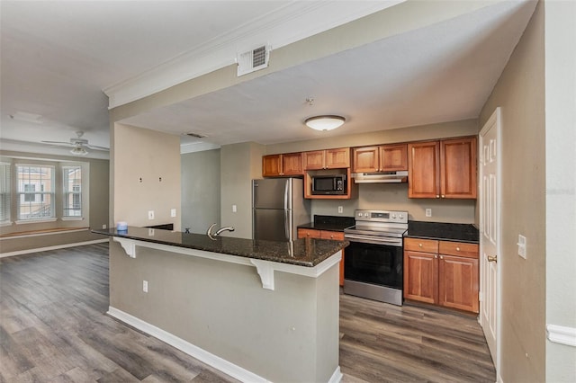 6611 Time Square Ave Unit 103, Orlando, FL 32835 - kitchen featuring stainless steel appliances, under cabinet range hood, a breakfast bar, dark wood-style flooring, and baseboards