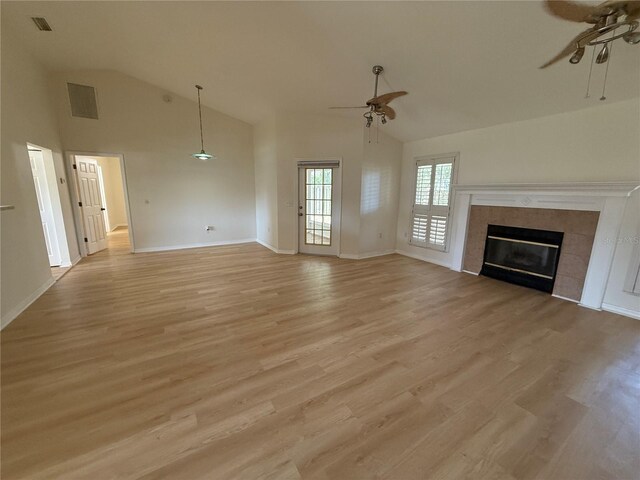 unfurnished living room with a ceiling fan, light wood-type flooring, a tiled fireplace, high vaulted ceiling, and baseboards