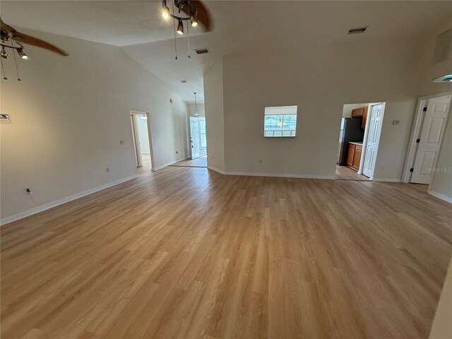 unfurnished living room featuring a ceiling fan, high vaulted ceiling, light wood-style floors, and baseboards
