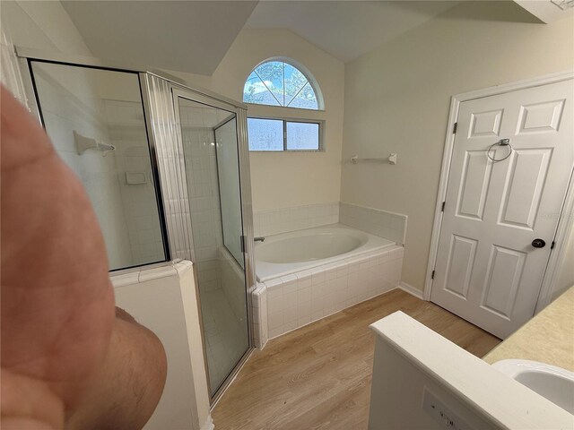 bathroom with wood finished floors, a garden tub, a stall shower, vaulted ceiling, and vanity
