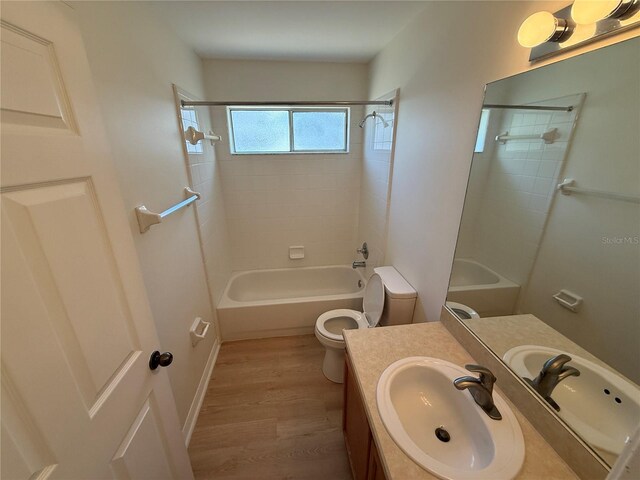 full bath with wood finished floors, toilet, vanity, and washtub / shower combination