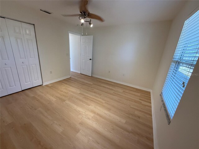 unfurnished bedroom with light wood-style flooring, baseboards, a ceiling fan, and a closet