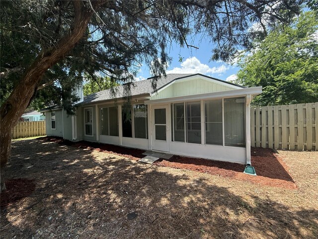 back of property with a sunroom and fence