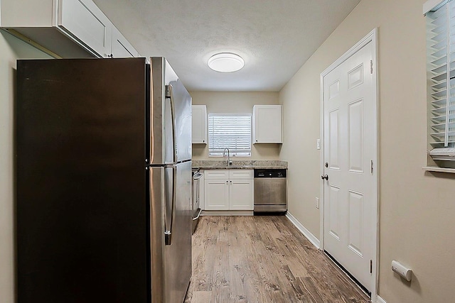 4812 N 37th St, Tampa, FL 33610 - kitchen with stainless steel appliances, white cabinets, light wood-type flooring, a sink, and light stone countertops