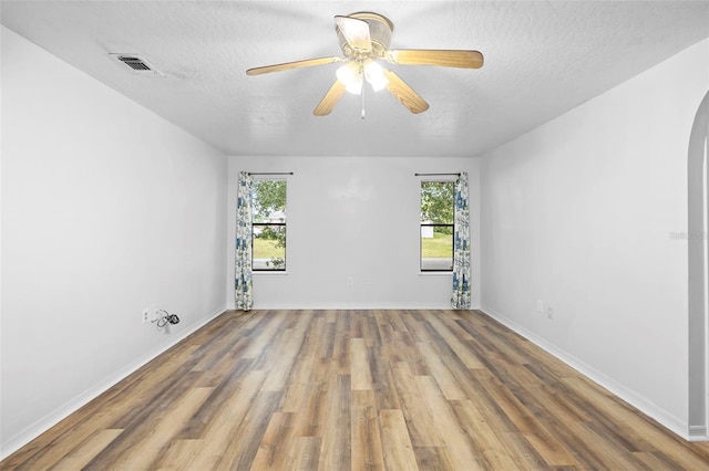 1106 Alpine Ave NW, Palm Bay, FL 32907 - spare room featuring healthy amount of natural light, wood finished floors, a textured ceiling, arched walkways, and baseboards