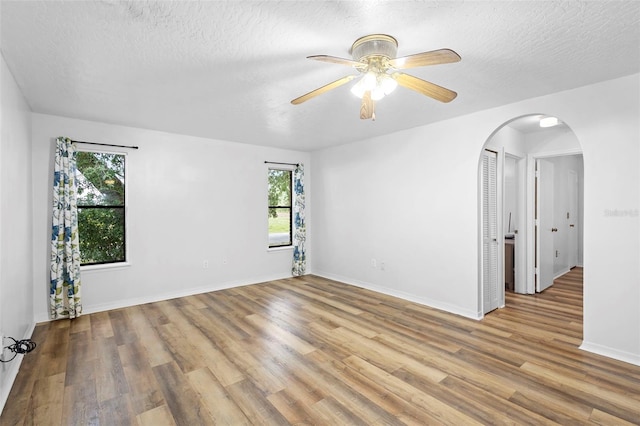 1106 Alpine Ave NW, Palm Bay, FL 32907 - spare room featuring healthy amount of natural light, arched walkways, wood finished floors, and a textured ceiling